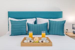 a tray of food on a bed with two glasses of orange juice at Apartments Bonazza in Petrovac na Moru