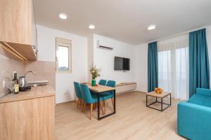a kitchen and living room with a table and a blue couch at Apartments Bonazza in Petrovac na Moru
