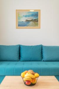 a blue couch with a bowl of fruit on a table at Apartments Bonazza in Petrovac na Moru