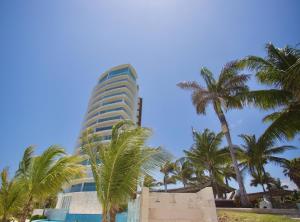 un edificio alto con palmeras delante en Ocean view 3 bedroom condo! Infinity pool, en Cancún