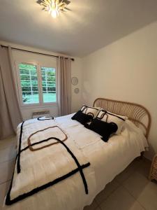 - une chambre avec un grand lit blanc et des oreillers noirs dans l'établissement Maison à 400 M de la plage de Pampelonne, à Saint-Tropez