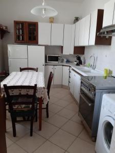 uma cozinha com armários brancos, uma mesa e um lavatório em Appartamento per Vacanze Domus Lunae em Luni