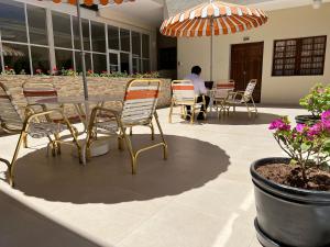 un hombre sentado en una mesa con sillas y un paraguas en Hotel Tito, en Arequipa