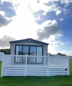 a small house with a white fence in the grass at 2-6 guests Holiday Home in Durdle Door in Wareham