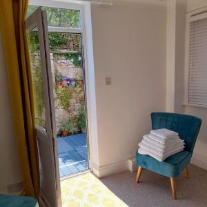 a room with a blue chair and a sliding glass door at The Hideaway in Swanage