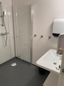 baño blanco con ducha y lavamanos en Fjordly Ungdomssenter en Bryggja