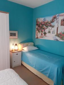 een blauwe slaapkamer met een bed en een schilderij aan de muur bij Olive House in Kalamaki