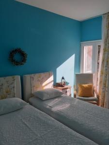 a bedroom with two beds and a blue wall at Olive House in Kalamaki