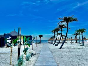 a path on the beach with palm trees and umbrellas at Signature PROMENADA Hotel Apartments in Mamaia Nord