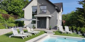 a villa with a swimming pool and chairs and a house at AQUA SOLAR APARTMANHÁZ in Miskolc