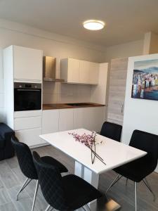cocina con mesa blanca y sillas negras en Apartment Mary, en Trogir