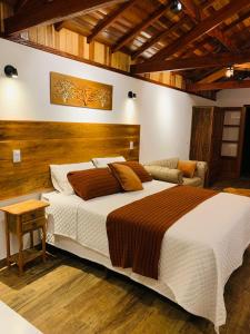 um quarto com uma cama grande e um sofá em Monte Verde Lofts Araucária em Monte Verde