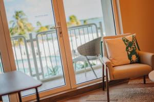 a room with a chair and a balcony with a view at Renaissance Wind Creek Aruba Resort in Oranjestad