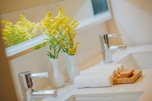 a bathroom sink with two vases with yellow flowers on it at Renaissance Wind Creek Aruba Resort in Oranjestad