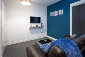 een woonkamer met een bruine leren bank en een blauwe muur bij Bank Street Apartment 9 in Blackpool
