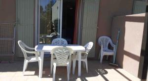 - une table et des chaises blanches sur la terrasse dans l'établissement Belle Maisonette dans Residence 3* avec piscine partagée, à Saint-Saturnin-lès-Avignon