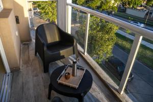 una mesa y una silla en el balcón con vistas a la calle en Departamento Sunset en Chascomús