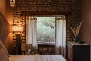 a bedroom with a window in a log wall at Our Habitas Atacama in San Pedro de Atacama