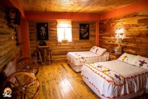 a bedroom with two beds in a log cabin at TARAMURI HOTEL & TOURS in Creel