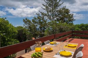 a wooden table with plates of food on a balcony at Matur I by An Island Apart in Água de Pena
