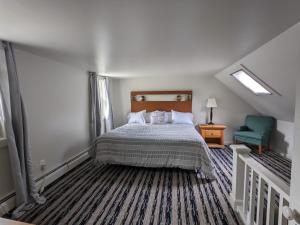 1 dormitorio con 1 cama y 1 silla verde en Perry's Motel and Cottages, en North Conway