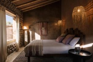 聖佩德羅·德·阿塔卡馬的住宿－Our Habitas Atacama，一间卧室配有一张床、一张桌子和一个窗户。