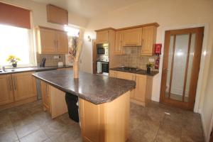 a kitchen with wooden cabinets and a granite counter top at Lundwood House Barnsley by Smart Corporate Stays in Barnsley