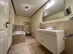 a bathroom with a sink and a tub and a toilet at Deichhof Whg Luana in Dunsum