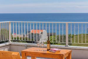 a table with wine glasses on a balcony with the ocean at Apartments Bonazza in Petrovac na Moru