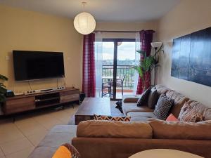 sala de estar con 2 sofás y TV de pantalla plana en Westpoint Suites by Senga en Nairobi