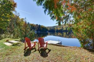 two red chairs sitting on the shore of a lake at Bécassines Private Spa & Pool table , Waterfront in Nominingue