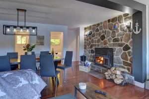 a living room with a stone fireplace and a dining room at Bécassines Private Spa & Pool table , Waterfront in Nominingue