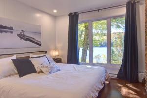 a bedroom with a bed and a large window at Bécassines Private Spa & Pool table , Waterfront in Nominingue
