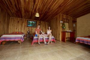 a man and woman sitting on beds in a room at Historias Lodge in Monteverde Costa Rica