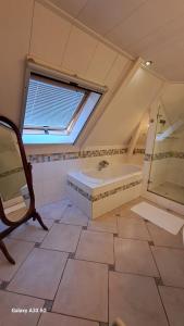 ein großes Bad mit einer Badewanne und einem Fenster in der Unterkunft B&B Het Oude Doktershuys 