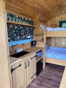 a kitchen in a log cabin with a sink and a bed at Woodie the shepherds hut - sleeps 4 in Chichester