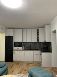 een keuken met witte kasten en een zwarte koelkast bij Apartment Shkoder in Shkodër