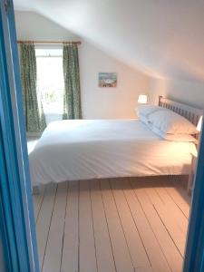 a bedroom with a large bed with white sheets and a window at Cherry Grove Welsh Farmhouse in Pembrokeshire