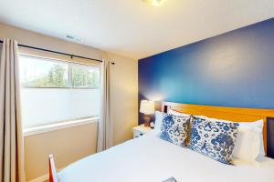 1 dormitorio con 1 cama con pared azul y ventana en Windsong Wander, en Cascade Locks