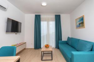 a living room with a blue couch and a table at Apartments Bonazza in Petrovac na Moru
