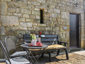 a table with a bottle of wine and flowers on a patio at Ladycroft House in Hebden