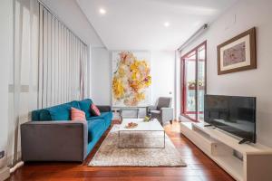 a living room with a blue couch and a flat screen tv at Chueca Gran Via Recoletos Libertad 24 12 in Madrid