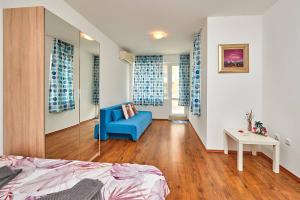 a room with a bed and a blue chair in it at Апартаменти Лазур на 200м от плажа с Безплатен Паркинг in Pomorie