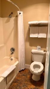 a bathroom with a toilet and a bath tub with towels at Morgan Inn and Suites Walla Walla in Milton-Freewater