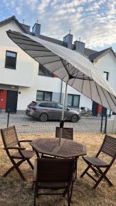a wooden table and chairs with an umbrella at Uroczy apartament z ogrodem in Rumia