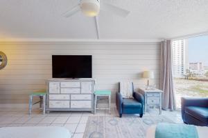 sala de estar con TV, sofá y silla en Top of the Gulf Experience en Panama City Beach