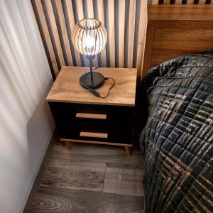 a lamp on a night stand next to a bed at Apartament przy Białym Koniu in Koszalin