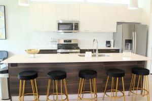 una cucina con bancone, sgabelli e lavandino di Modern Minimalist Luxury Retreat a Houston