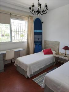 a bedroom with two beds and a desk and a chandelier at Caños de Meca Apartamento frente al mar in Los Caños de Meca