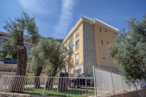 a yellow building with trees in front of it at Apartments Bonazza in Petrovac na Moru